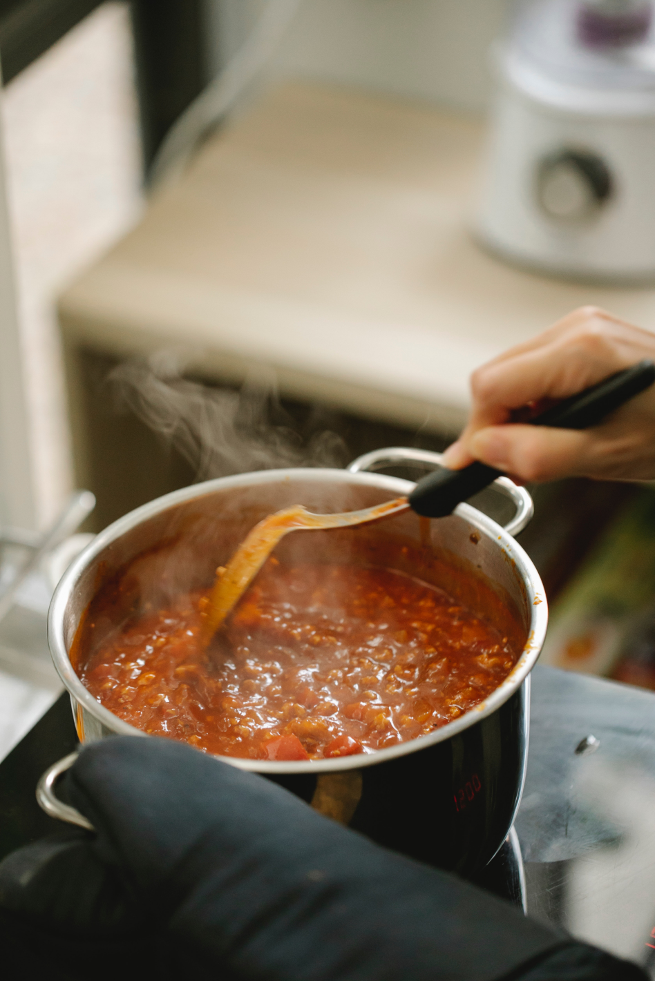 main qui brasse une sauce à spaghetti